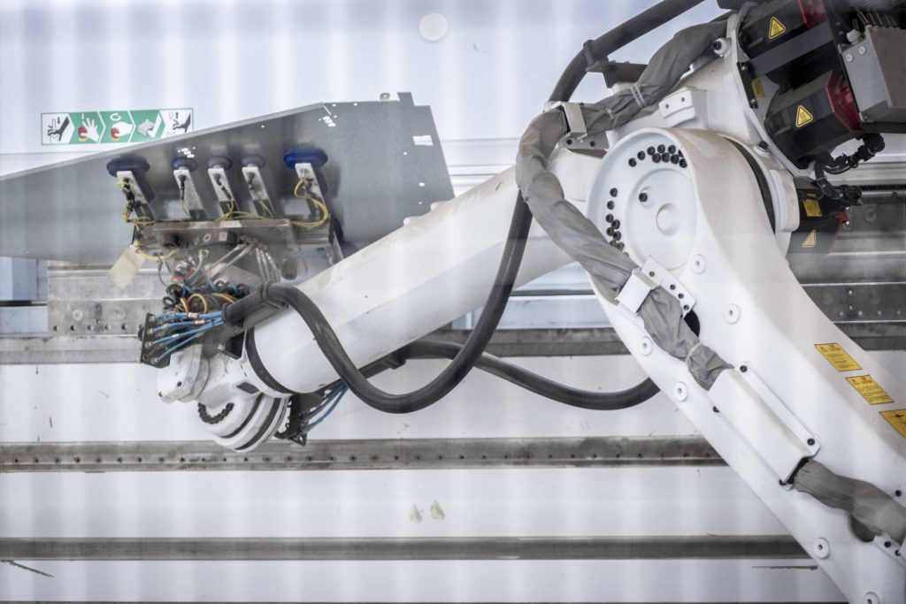 Braccio robotizzato con pinza a ventose che sostiene la lamiera
