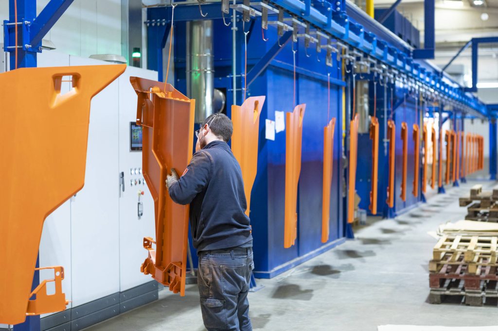 Operatore che aggancia i pezzi alla linea di verniciatura a polvere